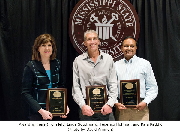 Three research Impact award winners with plaques