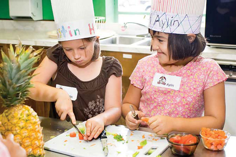 student cutting fruits and vegetables at camp