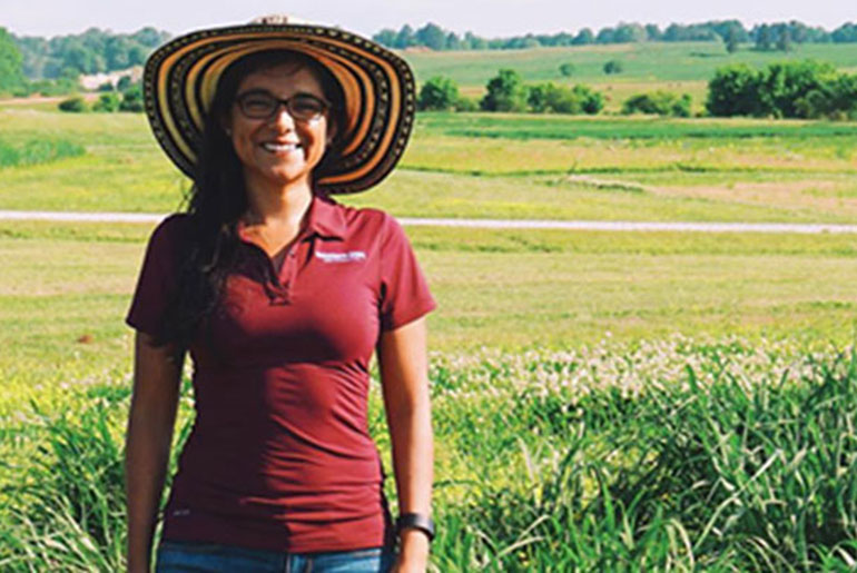 Female student in front of row crop farm