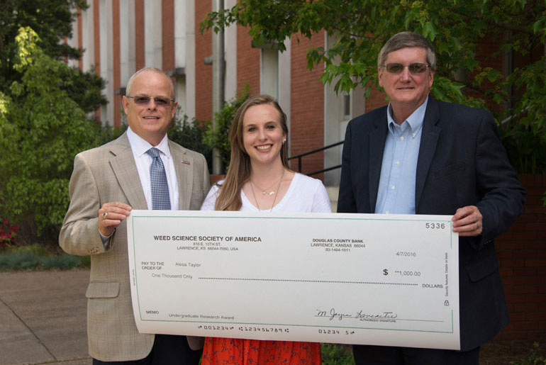 Two faculty present check to female student