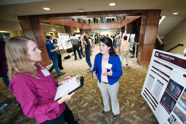 female student explains research in front of poster