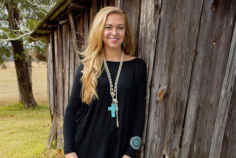 female student poses at old barn