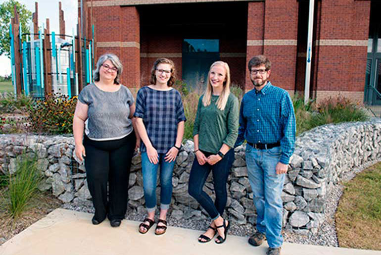 four individuals in front of rain garden