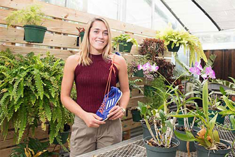 female student in greenhouse with track shoe