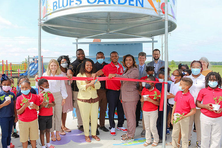 Leflore County Elementary School Principal April Smith cuts the ribbon as students and other leaders from the local area and Mississippi State University look on during a May 19 ribbon cutting ceremony for the new blues-themed learning garden.