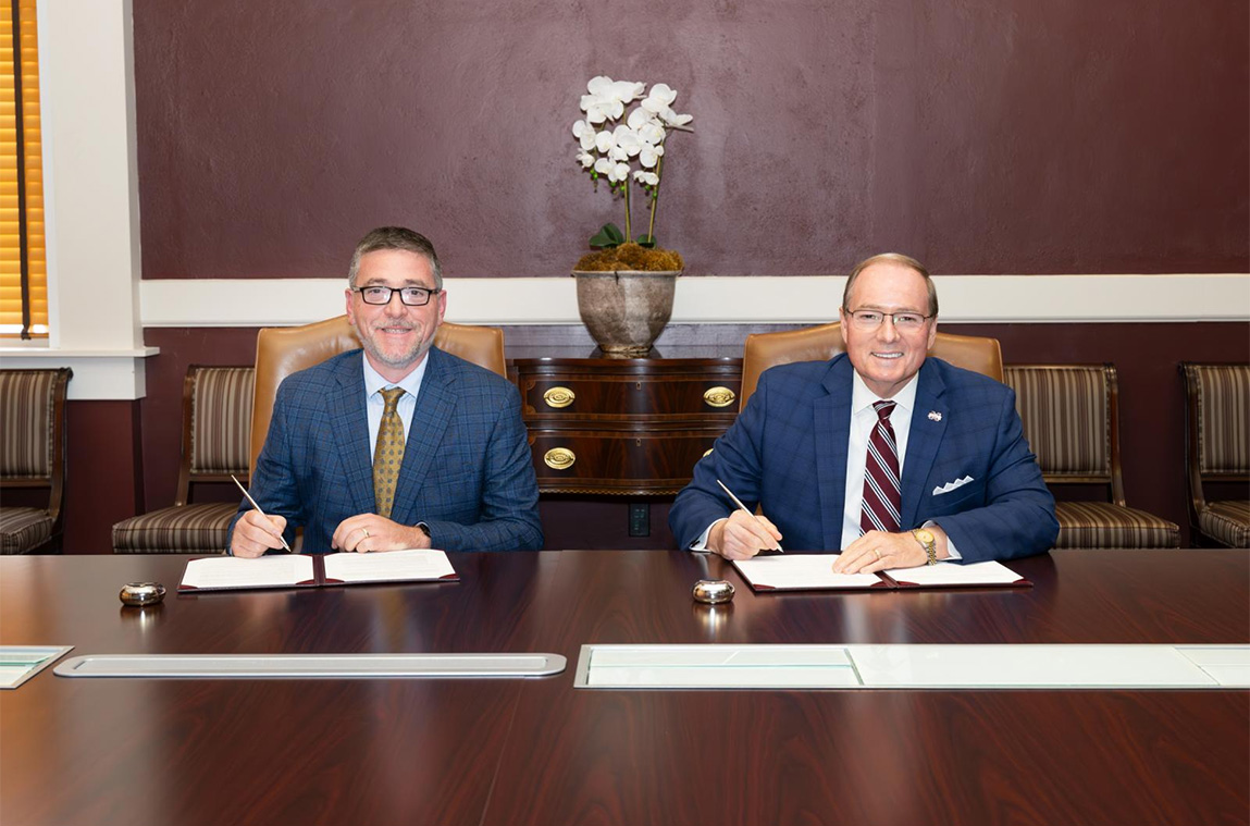 Two men at a table signing documents