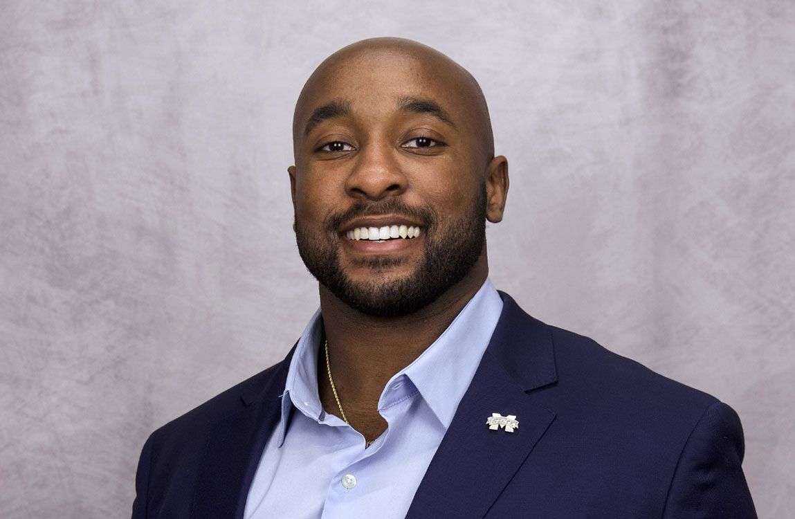 studio portrait of a man in a blue blazer with a gray background