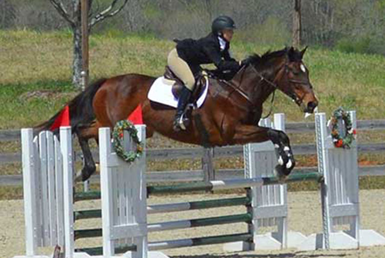 Student jumping fences on horse