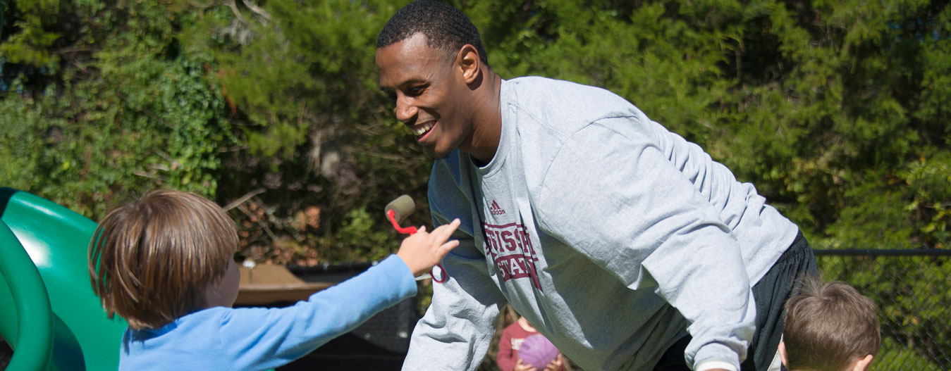 Male student playing with children