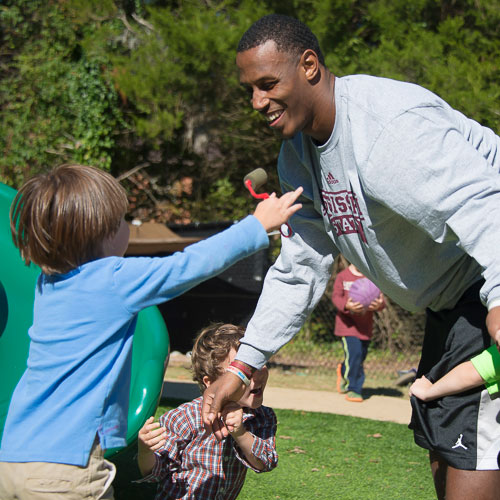 Male student playing with children